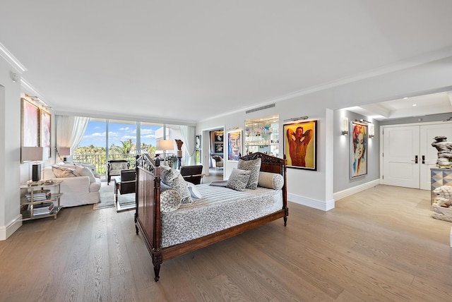 bedroom with a wall of windows, visible vents, baseboards, and wood finished floors