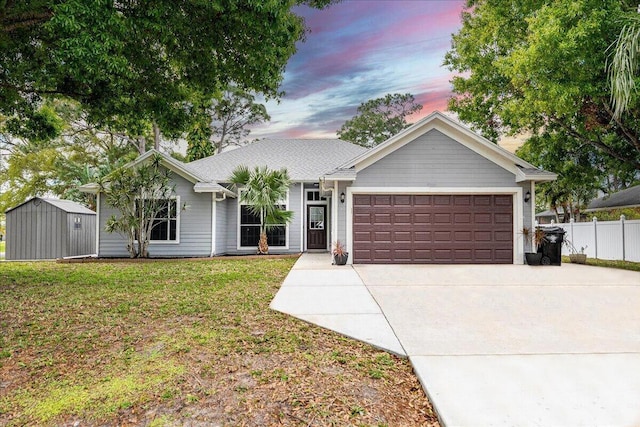 ranch-style house with a garage, concrete driveway, fence, a yard, and a shed