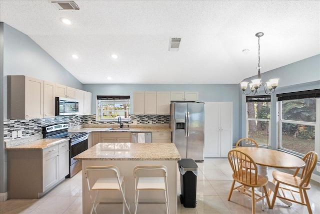 kitchen featuring lofted ceiling, visible vents, a kitchen island, and appliances with stainless steel finishes