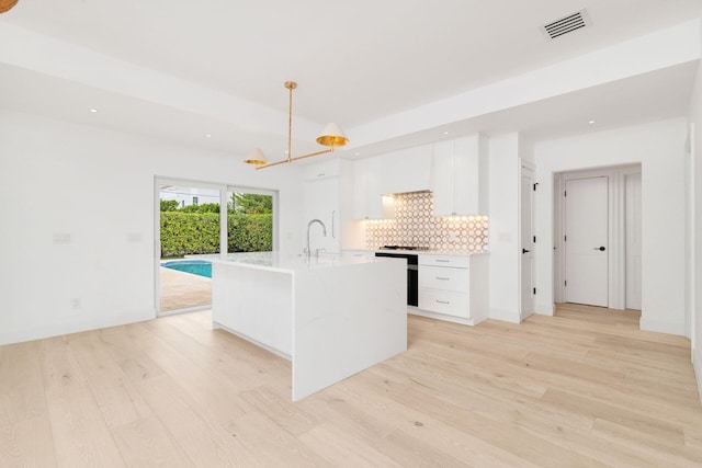 kitchen featuring light countertops, visible vents, light wood-style flooring, decorative backsplash, and white cabinetry