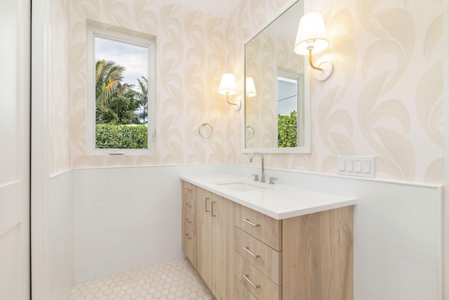 bathroom with wainscoting, vanity, and wallpapered walls