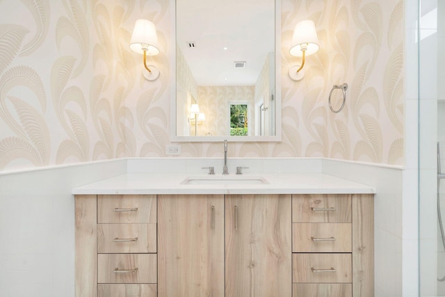 bathroom featuring visible vents, vanity, and wallpapered walls