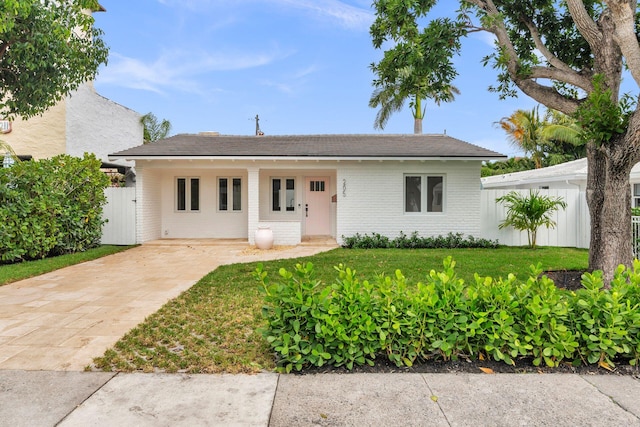 ranch-style home with brick siding, a front lawn, and fence