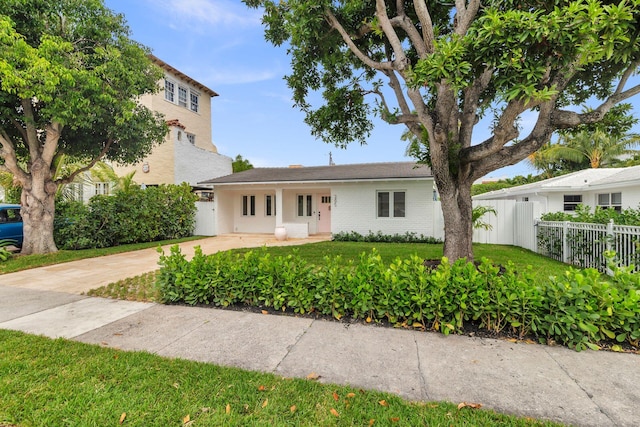 view of front of property with driveway, brick siding, fence, and a front yard