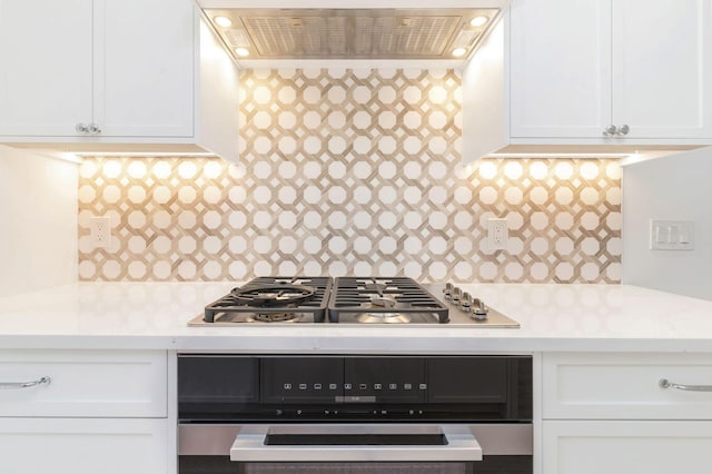 kitchen with range hood, tasteful backsplash, light countertops, stainless steel gas stovetop, and white cabinetry