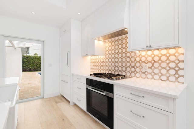 kitchen featuring light countertops, stainless steel gas stovetop, backsplash, wall oven, and white cabinetry