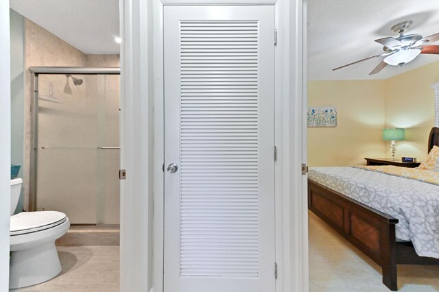 bathroom featuring ceiling fan, a closet, a shower stall, and toilet