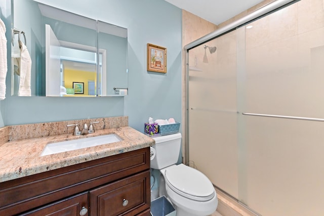 full bathroom featuring a shower stall, toilet, and vanity