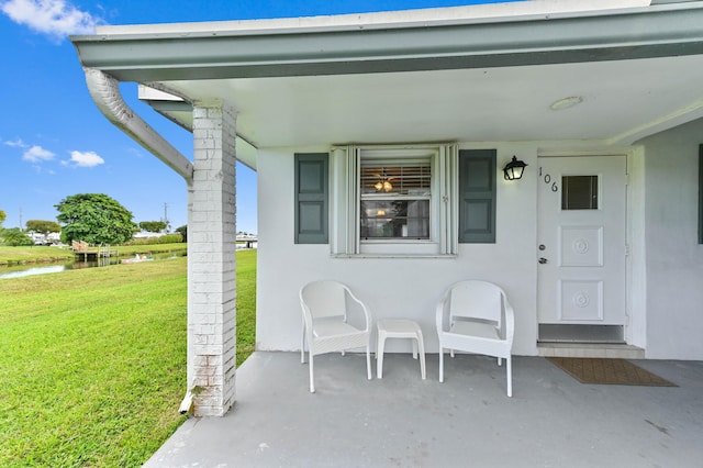 property entrance featuring a water view, a lawn, and stucco siding