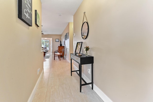 corridor featuring baseboards and light tile patterned flooring