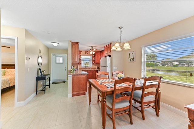 dining area featuring baseboards, a water view, light tile patterned flooring, and a notable chandelier