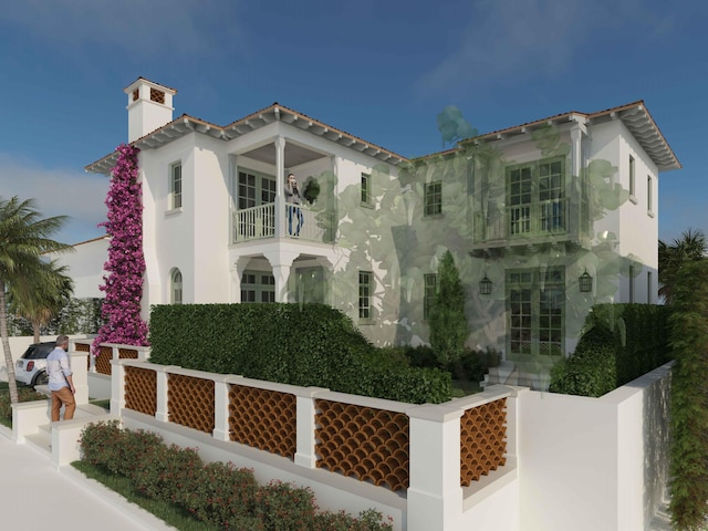 mediterranean / spanish-style house featuring a balcony, a fenced front yard, a chimney, and french doors