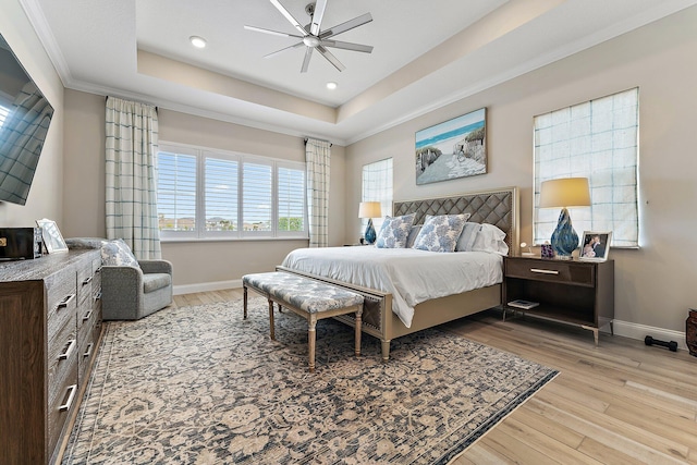 bedroom featuring ornamental molding, a raised ceiling, baseboards, and wood finished floors