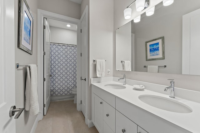 full bath featuring double vanity, a sink, toilet, and tile patterned floors