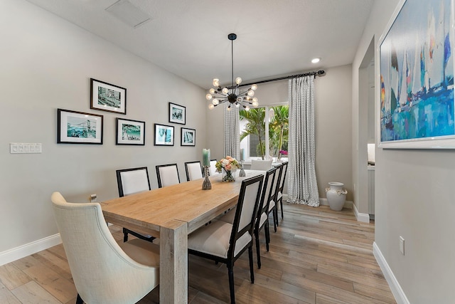 dining space featuring light wood finished floors, visible vents, baseboards, and an inviting chandelier