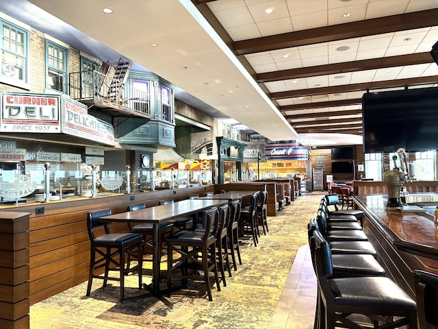 dining space with a dry bar and beam ceiling