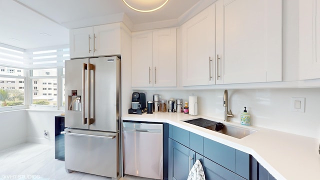 kitchen with stainless steel appliances, a sink, light countertops, and white cabinets