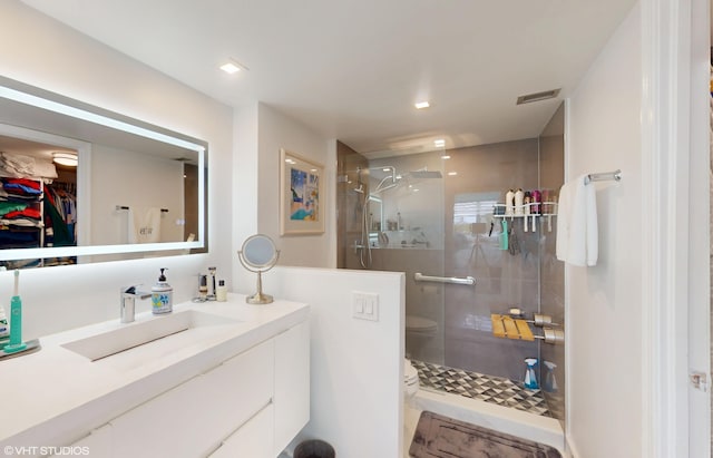 full bath with a stall shower, a spacious closet, visible vents, and vanity