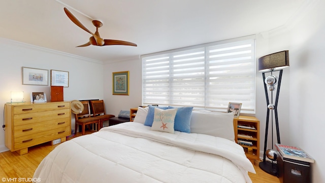 bedroom featuring light wood-style floors, crown molding, and a ceiling fan