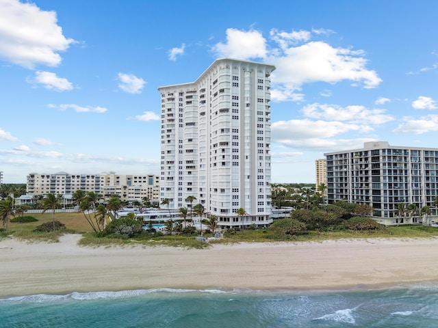 view of building exterior featuring a city view, a water view, and a beach view