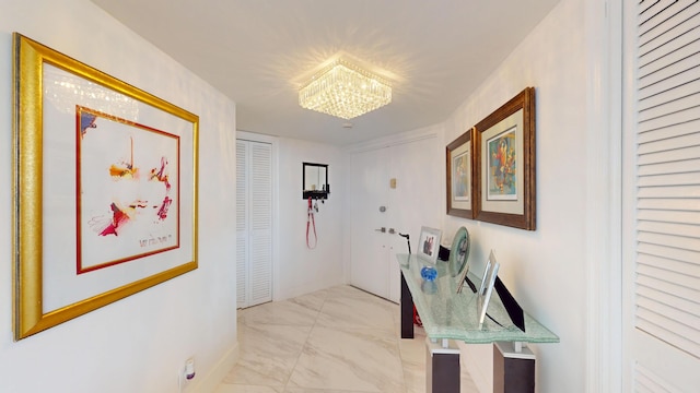 hallway with a chandelier and marble finish floor