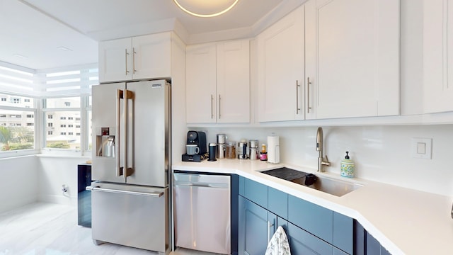 kitchen featuring stainless steel appliances, white cabinets, light countertops, and a sink