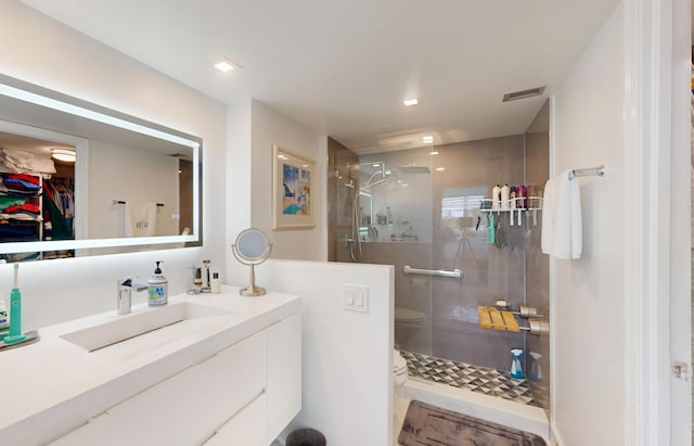 full bath featuring vanity, a spacious closet, a shower stall, and visible vents