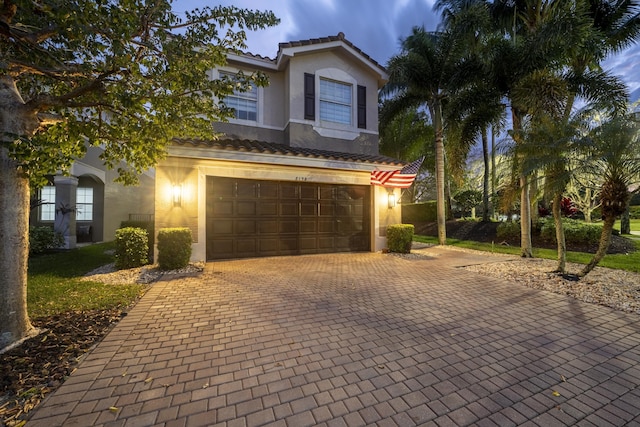 view of front of home featuring a garage, decorative driveway, a tiled roof, and stucco siding