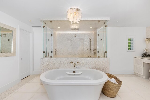 bathroom featuring a soaking tub, tile patterned floors, vanity, a shower stall, and a notable chandelier