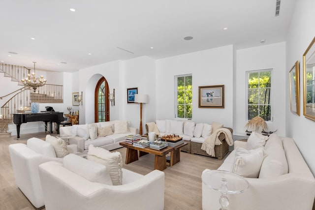 living area featuring light wood-style floors, recessed lighting, stairway, and an inviting chandelier