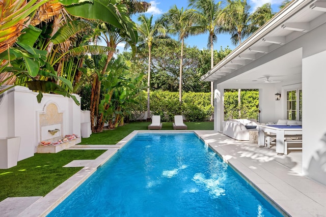 view of pool with a fenced in pool, a yard, a patio, ceiling fan, and an outdoor fireplace