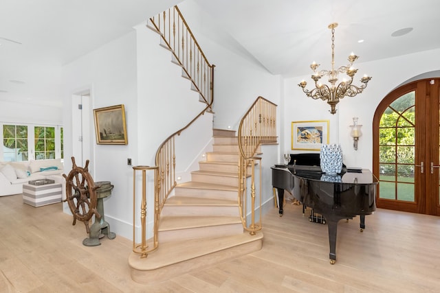 entrance foyer featuring stairway, arched walkways, wood finished floors, and french doors