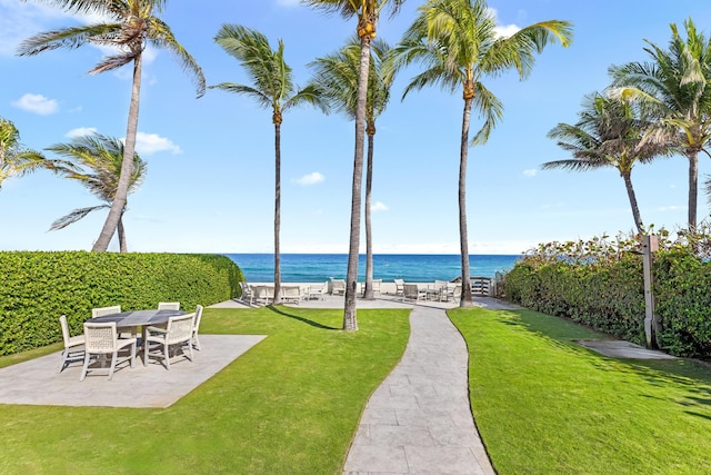 view of community with a patio, a yard, and a water view