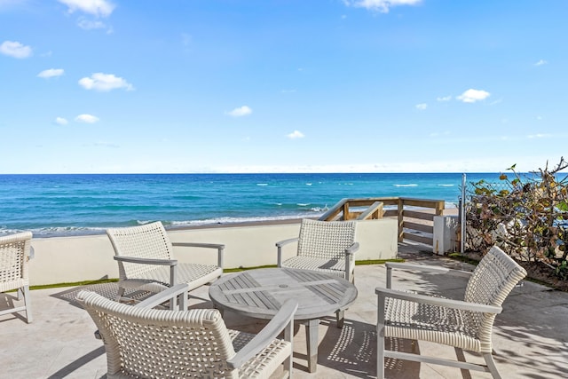 view of patio with a water view and a beach view