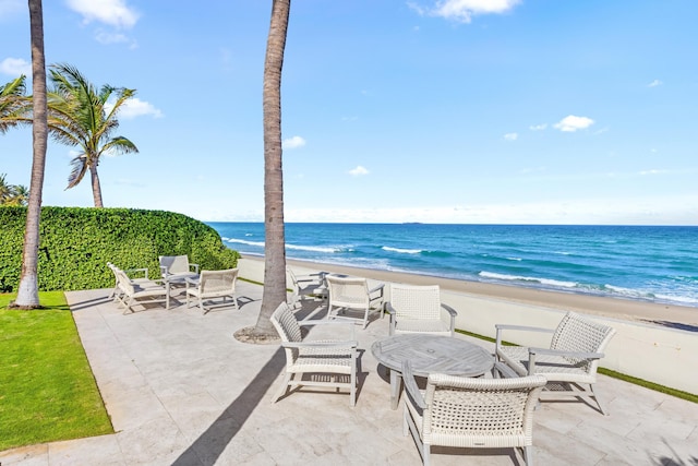 view of patio / terrace featuring a water view and a beach view