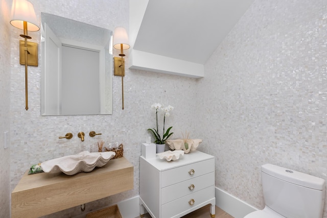 half bathroom featuring lofted ceiling and toilet