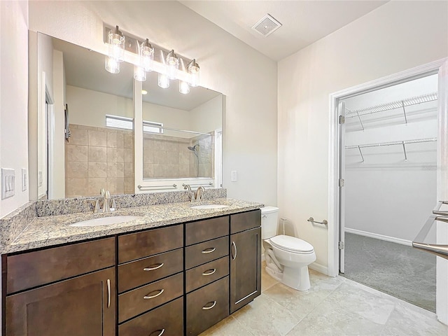 bathroom with visible vents, a sink, a spacious closet, and tiled shower