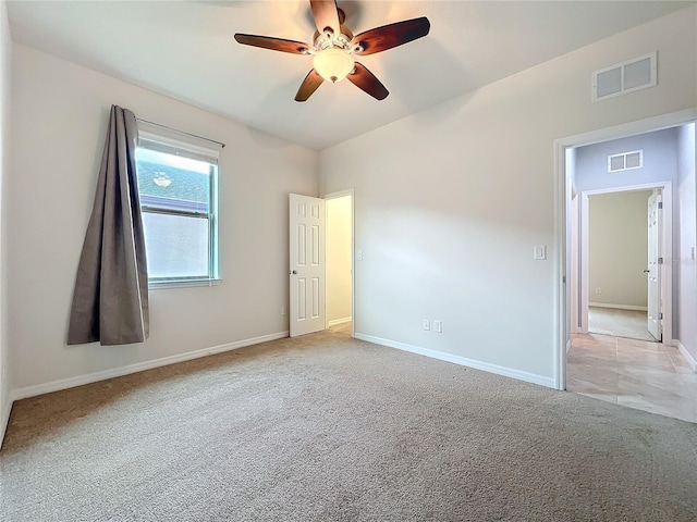 empty room featuring baseboards, ceiling fan, visible vents, and light colored carpet