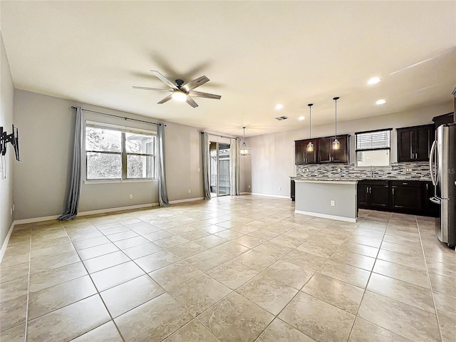 kitchen with open floor plan, a center island, decorative light fixtures, freestanding refrigerator, and light countertops