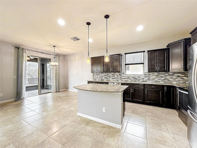 kitchen with dark brown cabinetry, light stone counters, pendant lighting, and a center island