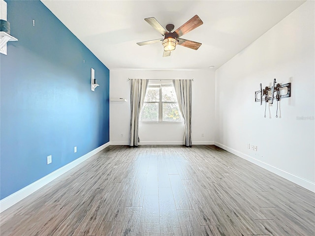 spare room with a ceiling fan, baseboards, and wood finished floors