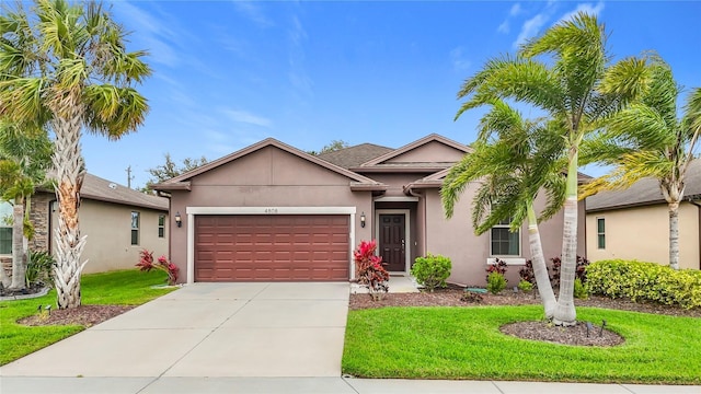 single story home featuring driveway, a front lawn, an attached garage, and stucco siding