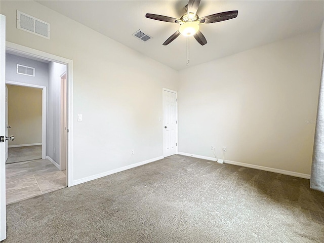 carpeted spare room with visible vents, ceiling fan, and baseboards