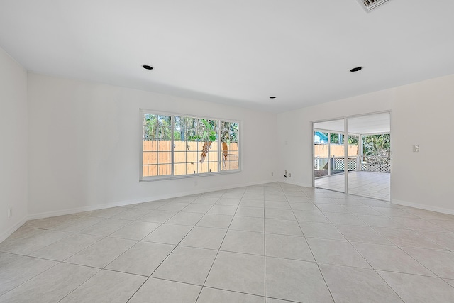 spare room with light tile patterned floors, visible vents, baseboards, and a wealth of natural light