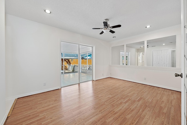 spare room with light wood-type flooring, ceiling fan, baseboards, and a textured ceiling