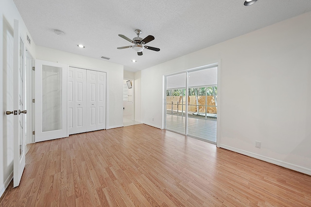 unfurnished bedroom with a textured ceiling, access to outside, light wood finished floors, and visible vents