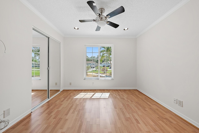 unfurnished bedroom featuring light wood-style floors, multiple windows, and a textured ceiling