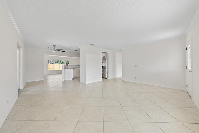 empty room with light tile patterned floors, crown molding, ceiling fan, and a textured ceiling