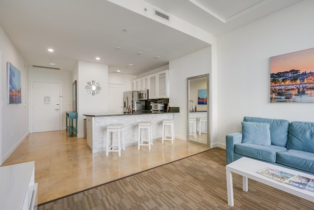 living room with baseboards, visible vents, light wood-style flooring, and recessed lighting