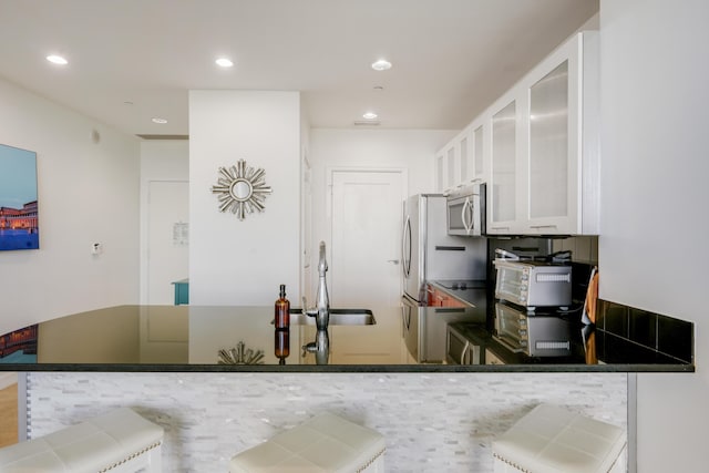 kitchen with white cabinetry, stainless steel microwave, a sink, and recessed lighting